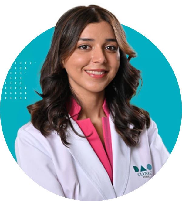 Smiling female clinician in a white coat with a pink blouse, posed against a teal circular background.